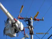 'Hot work', while tying a conductor back into the insulator on the crossarm. The Line Crew working on the utility pole.